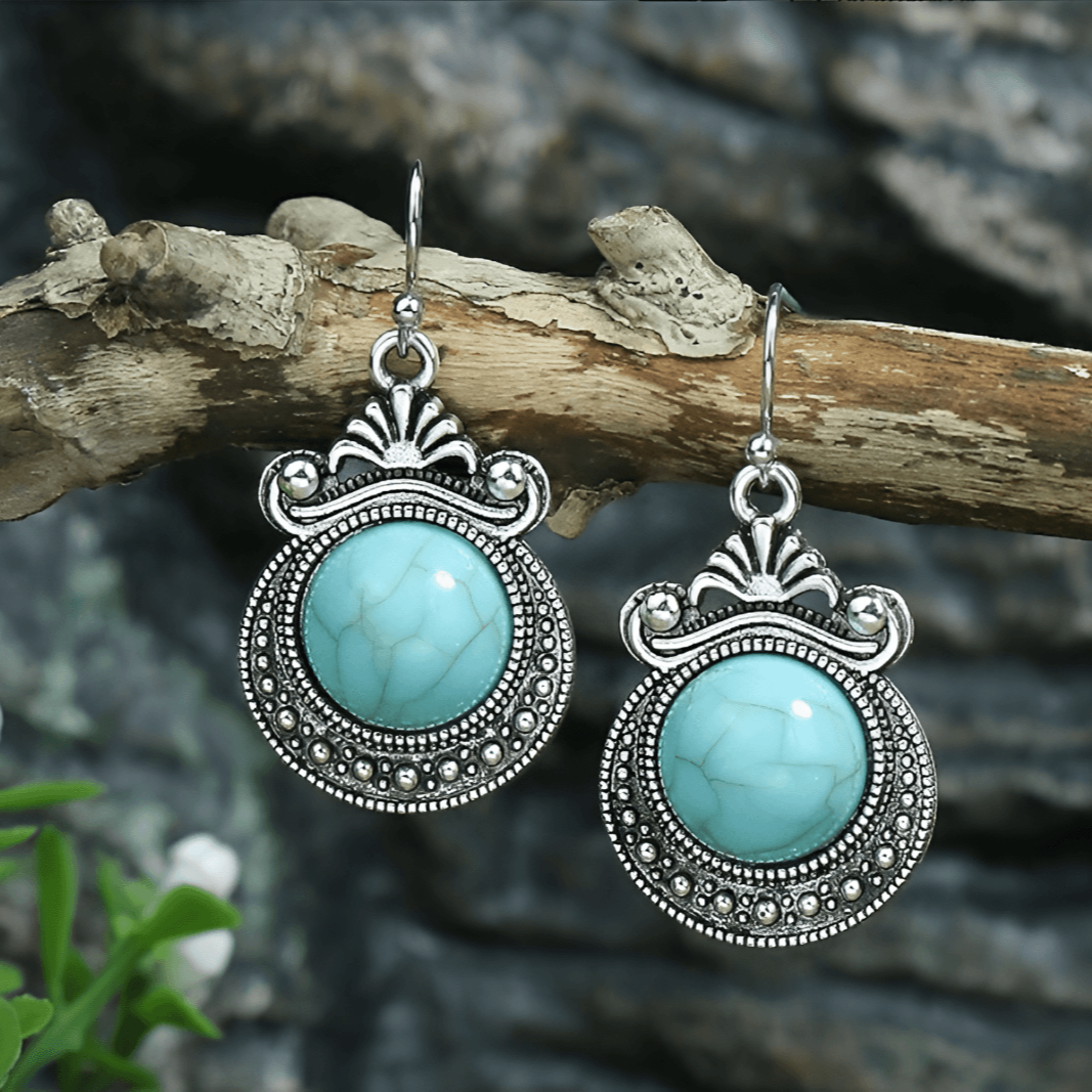 Turquoise earrings with silver detailing on a branch