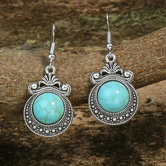 Pair of turquoise earrings with silver detailing on a wooden surface