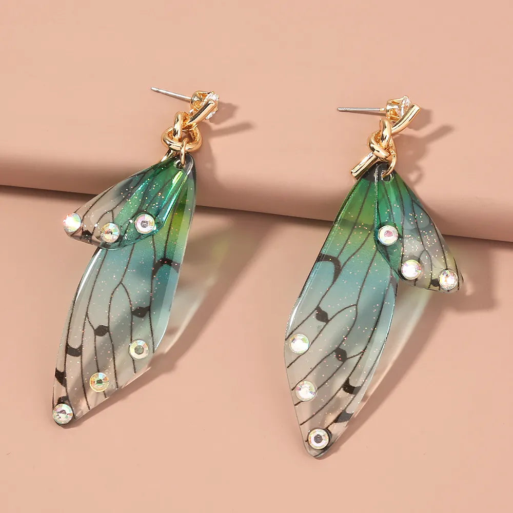 A pair of butterfly earrings with ocean blue and green colors, featuring hypoallergenic gold-colored hooks.