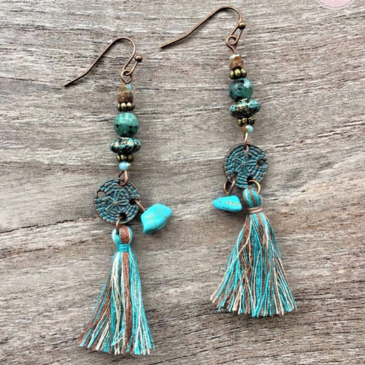 Turquoise beaded earrings with tassels on a wooden surface, branded 'LOVE LYDIA'.